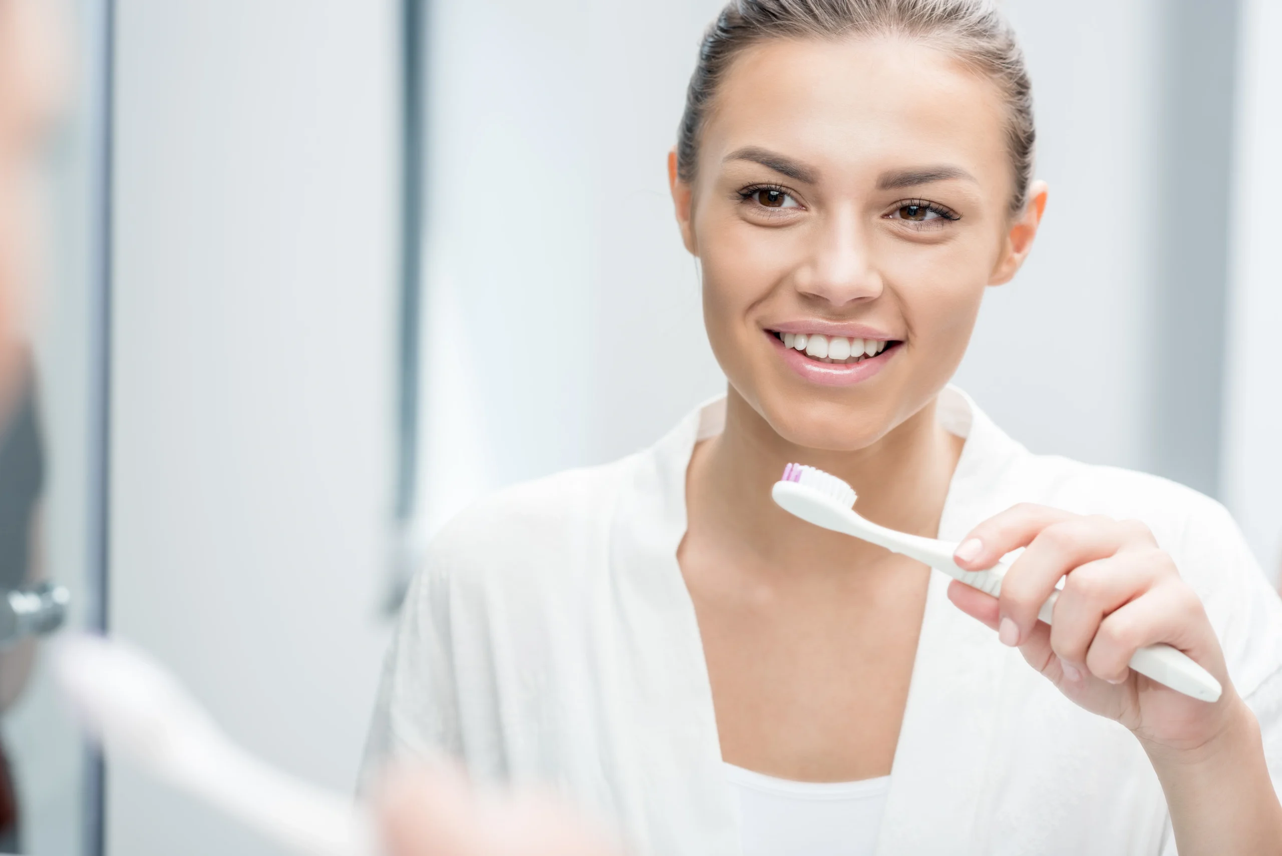 woman-starting-in-mirror-holding-a-toothbrush-about-to-brush-her-teeth