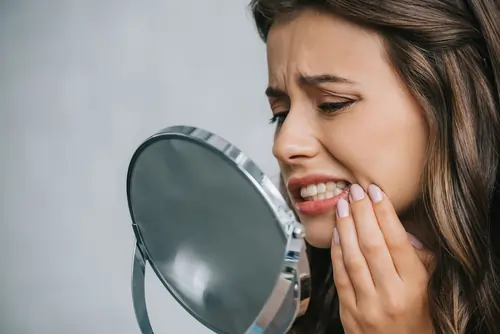 Woman staring at mirror while inspecting her teeth