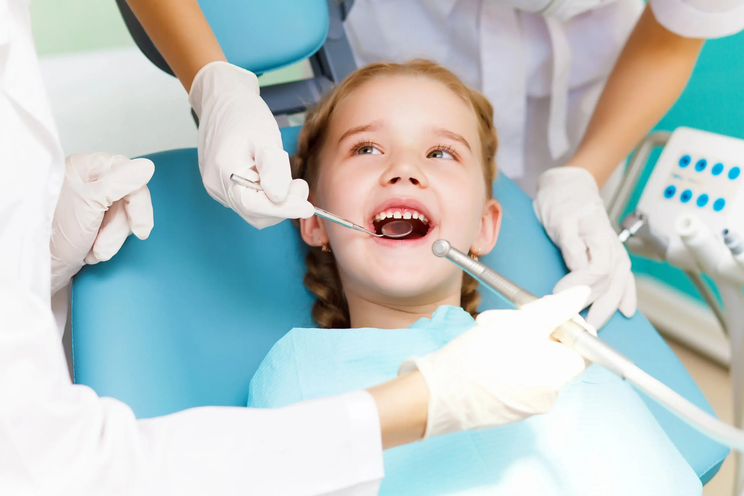 A child getting a check up while seated on a dentist chair.