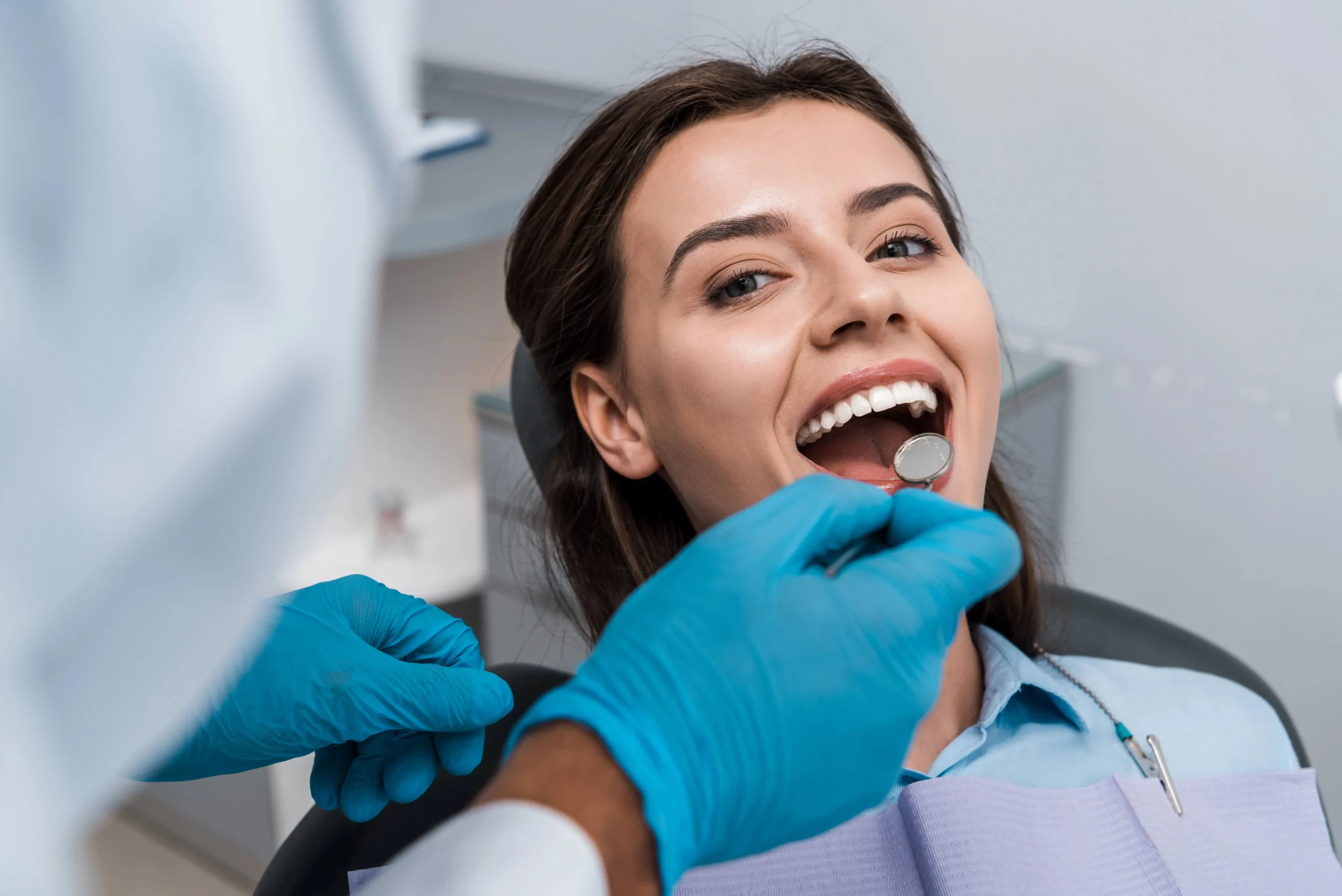 A young woman seated on a dentist chair getting her teeth checked