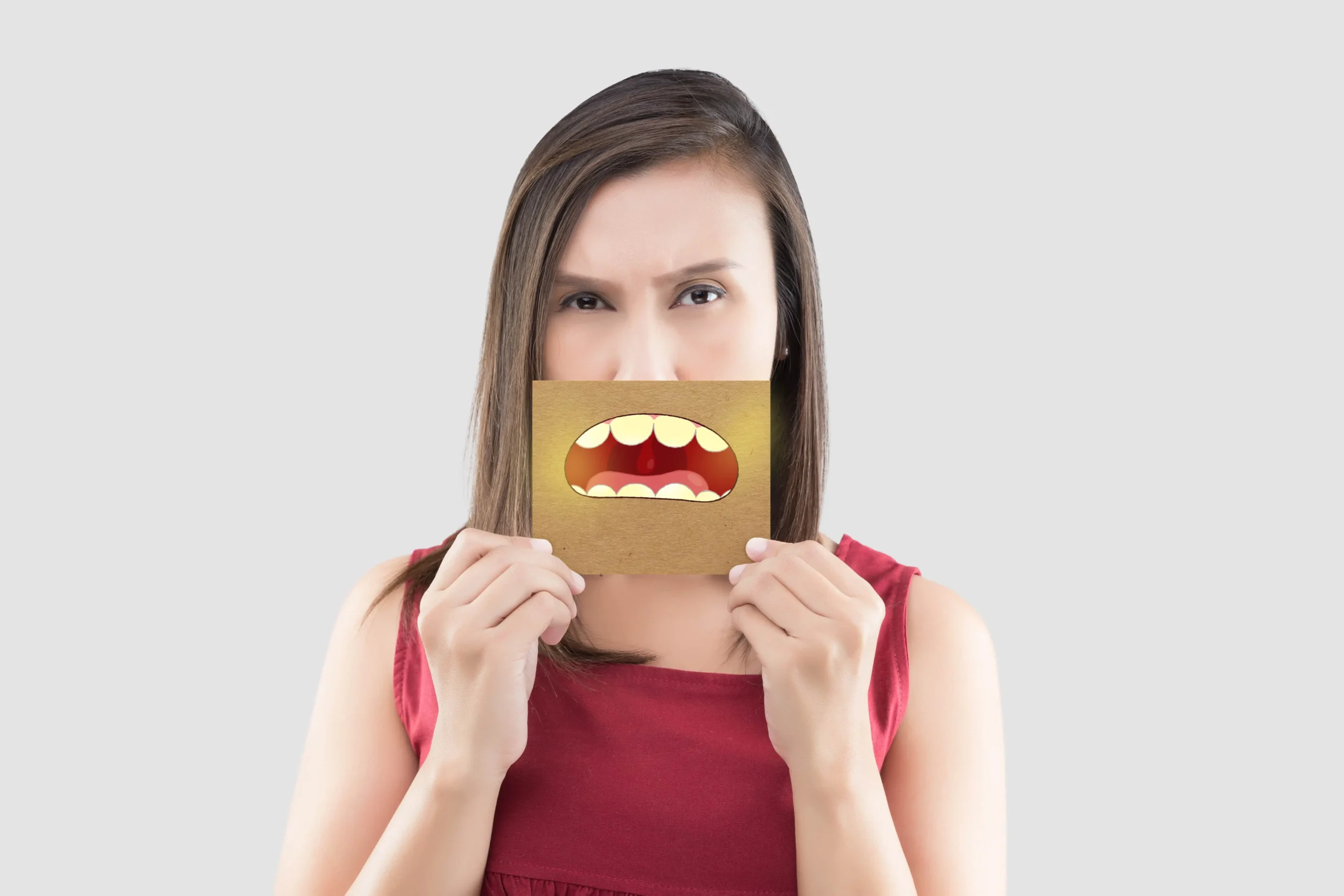 Woman holding a board that highlights her yellow teeth